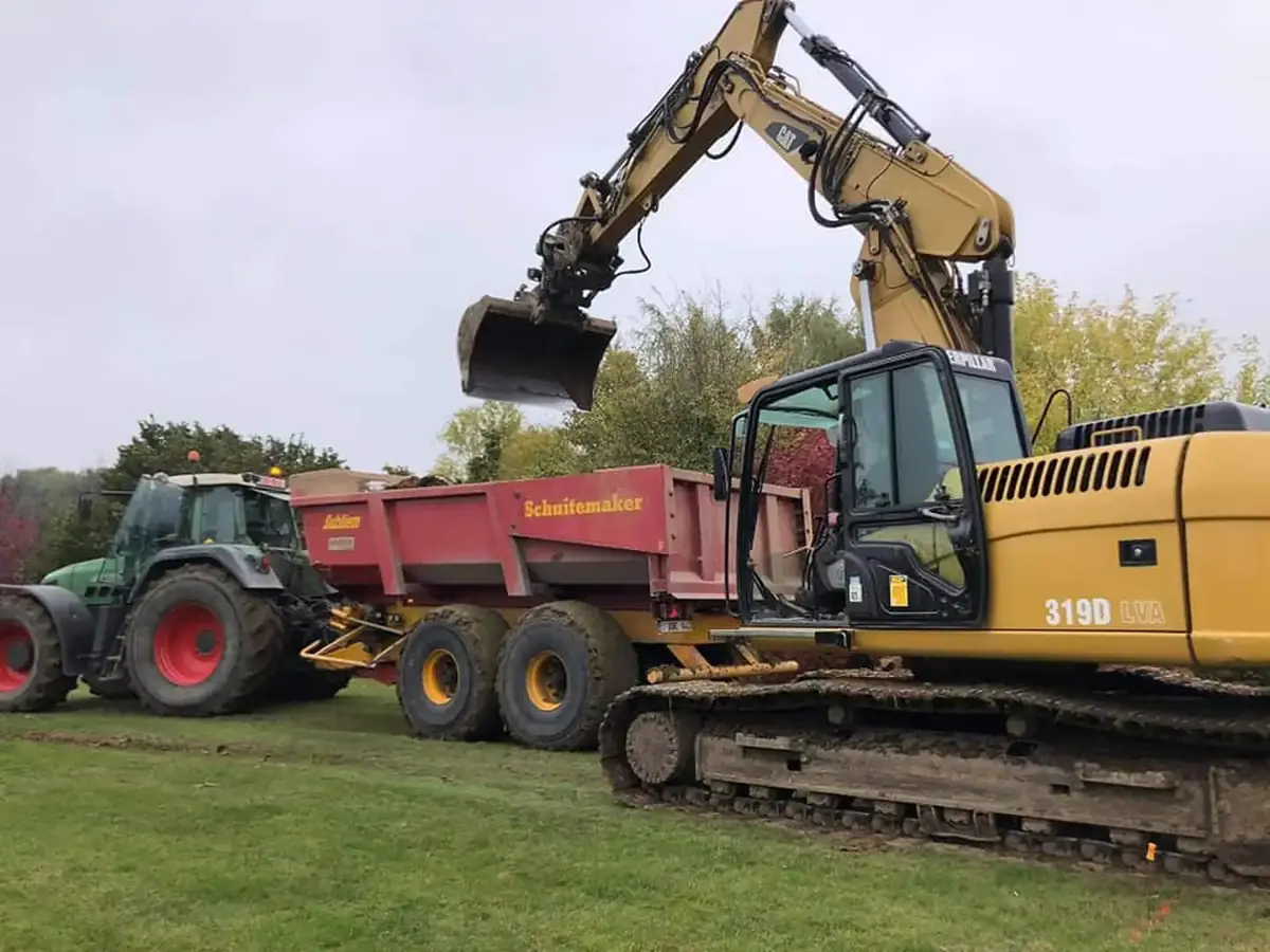 Pelle sur chenilles et benne attelée à un tracteur